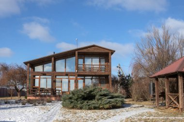 Kışın panoramik pencereleri ve terası olan modern ahşap kır evi.