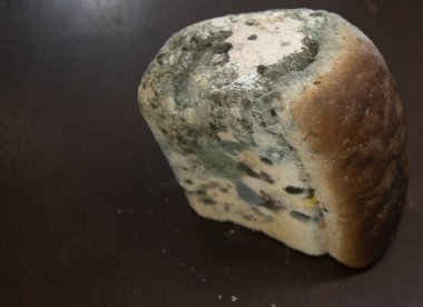 Ahşap masada yeşil mantarlı küflü beyaz ekmek.