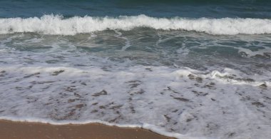 Deniz köpüğü ve mavi suyla Kumsala yuvarlanan Okyanus Dalgaları