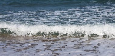 Deniz köpüğü ve mavi suyla Kumsala yuvarlanan Okyanus Dalgaları