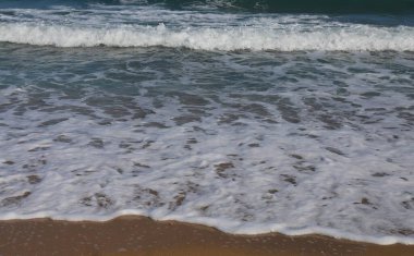 Hafif Deniz Dalgaları Parlak Güneşli bir günde kumsalda süzülüyor