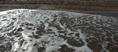 Güneşli bir günde Doğal Sahilde Deniz Köpüğü Kuma Süzülüyor