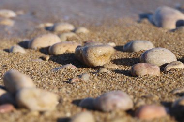 Yumuşak okyanus arkaplanlı kumsala serpilmiş yumuşak deniz çakıl taşları