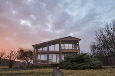 Büyük pencereli ahşap yazlık ve kırsal kesimde gün batımında balkon.