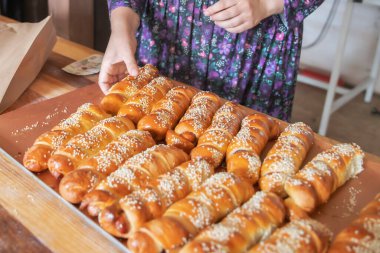 Hamura sarılmış sosisli börekler ve susam tohumları.