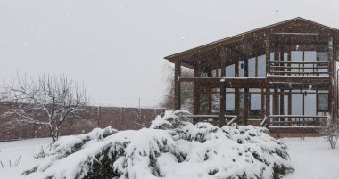 Kışın karlı arazide satılık modern ahşap aile evi.