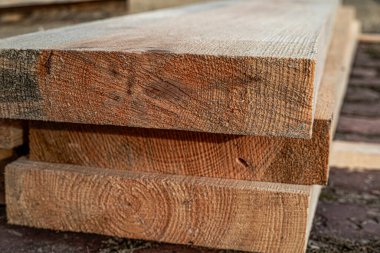 Kaba kesim ahşap tahtalar açık havada istiflenmiş doğal kereste ve testere dokusunu gösteriyor.