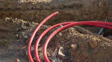 Yeraltı tesisatı inşaatı sırasında sipere yerleştirilen kırmızı plastik borular