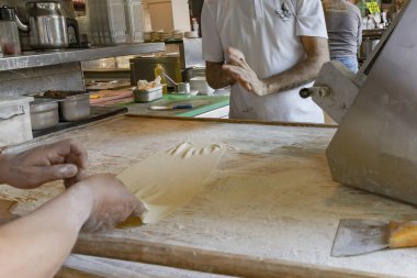 Fırıncı ekmek hazırlığı sırasında ahşap masaya elle taze hamur geriyor.