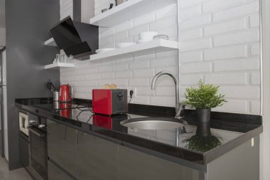 Ekmek dilimleri kırmızı mutfak tost makinesinin içinde modern ev mutfağının içindeki siyah tezgahta.