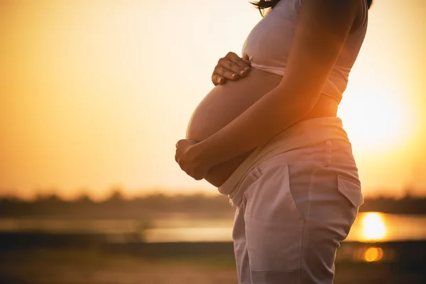 Pregnant woman relaxing lakeside sunset background — Stock Photo, Image