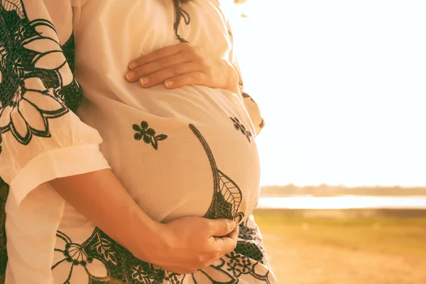 Pregnant woman relaxing lakeside sunset background — Stock Photo, Image