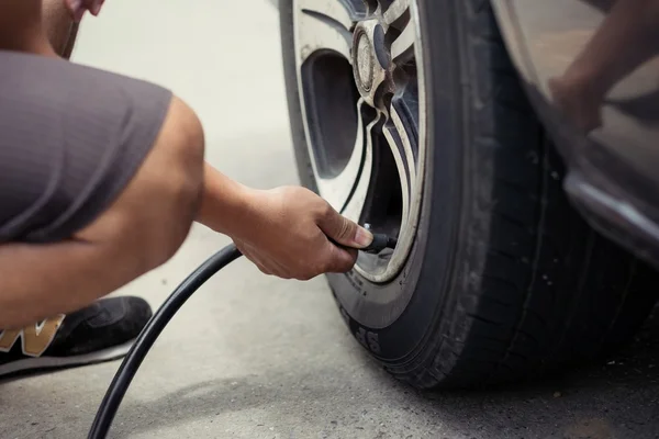 Man driver checking air pressure and filling air in the tires of