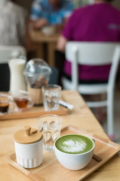 设置在 coffeshop 的木桌上的绿色热茶 — 图库照片