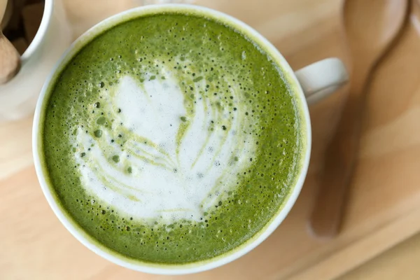 Varmt grönt te på ett träbord i en coffeshop — Stockfoto