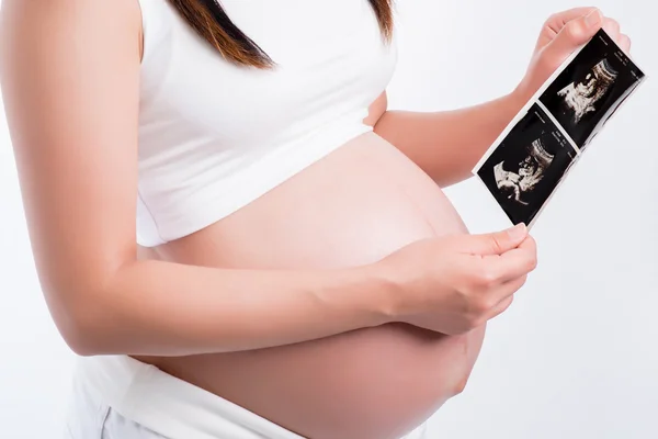 Mujer embarazada sosteniendo ecografía en su barriga — Foto de Stock