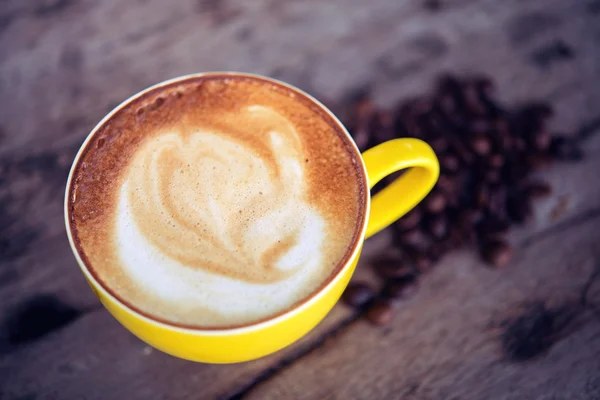 Café mocha quente e grãos de café na mesa de madeira — Fotografia de Stock