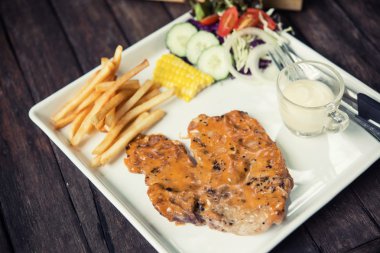 Bir ahşap masa restoran yer domuz biftek seti.