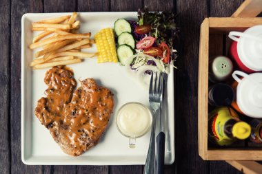 Bir ahşap masa restoran yer domuz biftek seti.