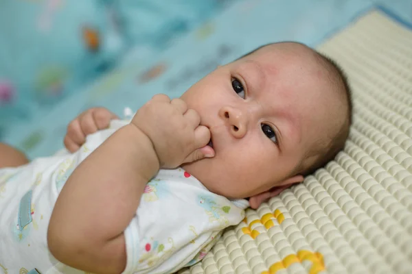 Bayi Asia tidur adalah mengisap linen tempat tidur putih . — Stok Foto