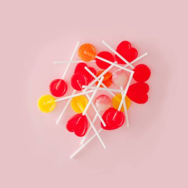 Pastel pembe arka planda bir sürü lolipop var. Yaratıcı renklendirme düzeni.