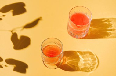 İçki bardakları ve yaprak gölgelerinden yapılmış yaratıcı asgari konsept fikir. Özgün yaz arkaplanı.