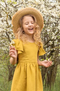 # Hasır şapkalı, yeşil elbiseli, çiçekli bir bahar bahçesinde #