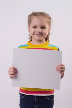 Renkli ceketli, saçları örgülü mutlu, sarışın bir kız ellerinde beyaz bir çarşaf tutuyor ve gülümsüyor.