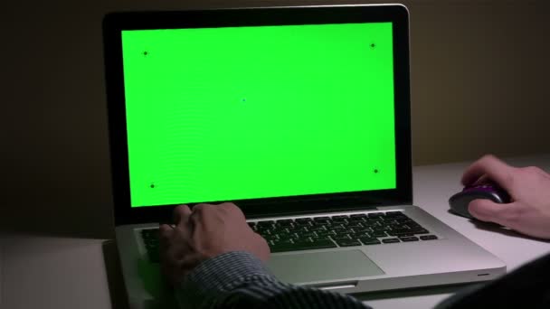 Um homem usa um laptop em seu desktop . — Vídeo de Stock