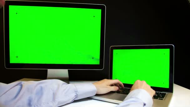 Человек, работающий над ноутбуком и дисплеем с зеленым экраном — стоковое видео