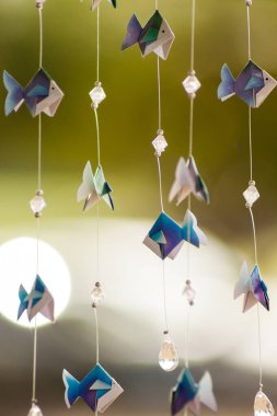 Origami balıklar ve boncuklar iplikler asılı, mağazada sergileniyor.