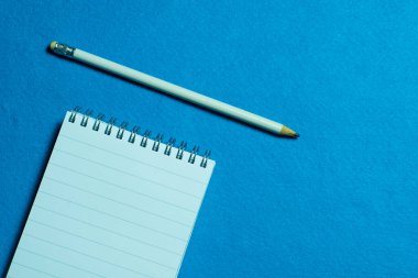 Açık mavi arkaplanda boş defter ve kalem sayfası