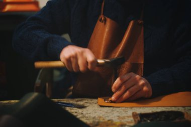 Sanatçının elleri çekiçle ve ağızla deri işliyor.
