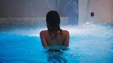 Yüzme havuzundaki kadının arkası. spa ve rahatlama