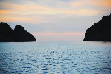 Gün batımında denizin üzerinde kara şeritleri