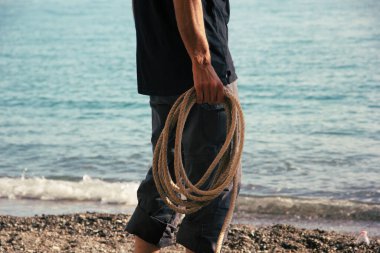 Sahildeki adam elinde bir ip tutuyor.