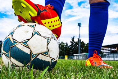 Futbol sahasında topa basan futbolcu ayağının altında gol var..