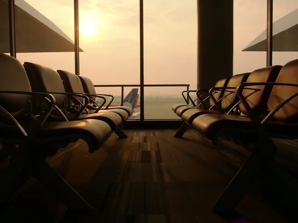 Havaalanı ve uçak yumuşak güneş ışığı altında arka planda boş koltuklarda Havaalanı bekleme salonu