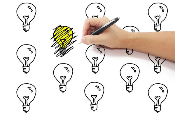 Hand with pen drawing scribbles on yellow light bulb idea among — Stock Photo, Image