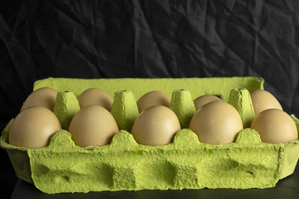 paper box with farm fresh chicken eggs on black background