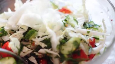 Kadın lahana parçalarını salataya çeviriyor.