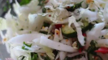 Kadın lahana parçalarını salataya çeviriyor.