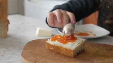 Kız kırmızı havyarlı sandviç hazırlıyor.