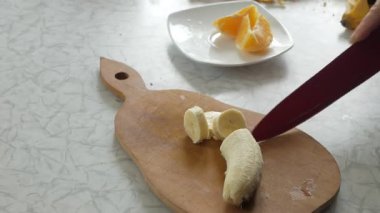 Kız mutfakta muz kesiyor.