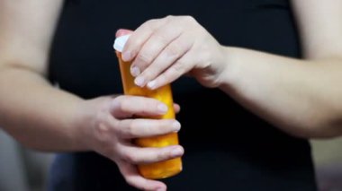 Turuncu kutudan beyaz ilaç alan bir kadın. Uyuşturucuları, hapları, hapları elden çıkarmak.