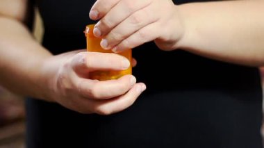 Turuncu kutudan beyaz ilaç alan bir kadın. Uyuşturucuları, hapları, hapları elden çıkarmak.