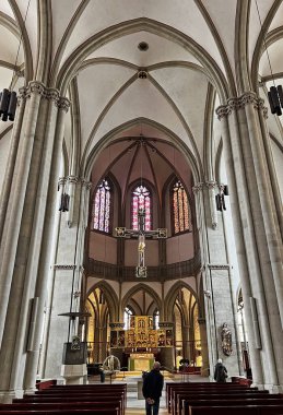 Osnabruk katedralinin geniş iç kısımları süzülen gotik kemerleri, boyalı camlı uzun pencereleri, bir haçı ve süslü bir sunağı gözler önüne serer..