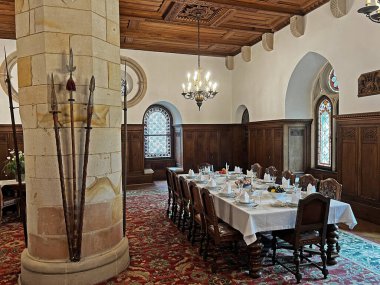 Bentheim Kalesi 'nde uzun bir sehpası, süslü ahşap panelleri, vitray pencereleri, taş bir kolonu ve tarihi silahları olan büyük bir yemek salonu.).