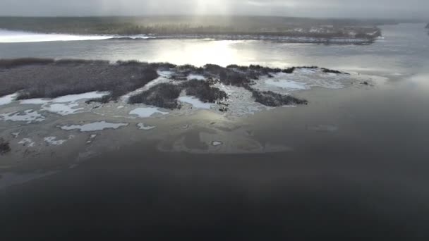 照相机在初冬用一台四轮式复印机捕捉河流 河上已经出现了一些冰 在河中央的一个岛 太阳反射在水面上 在河岸上有一片森林 — 图库视频影像