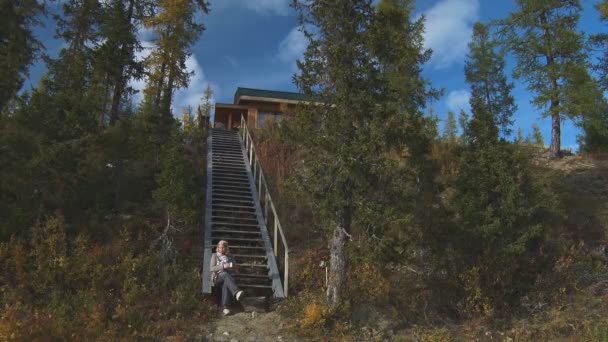 Frau sitzt auf Holztreppe — Stockvideo